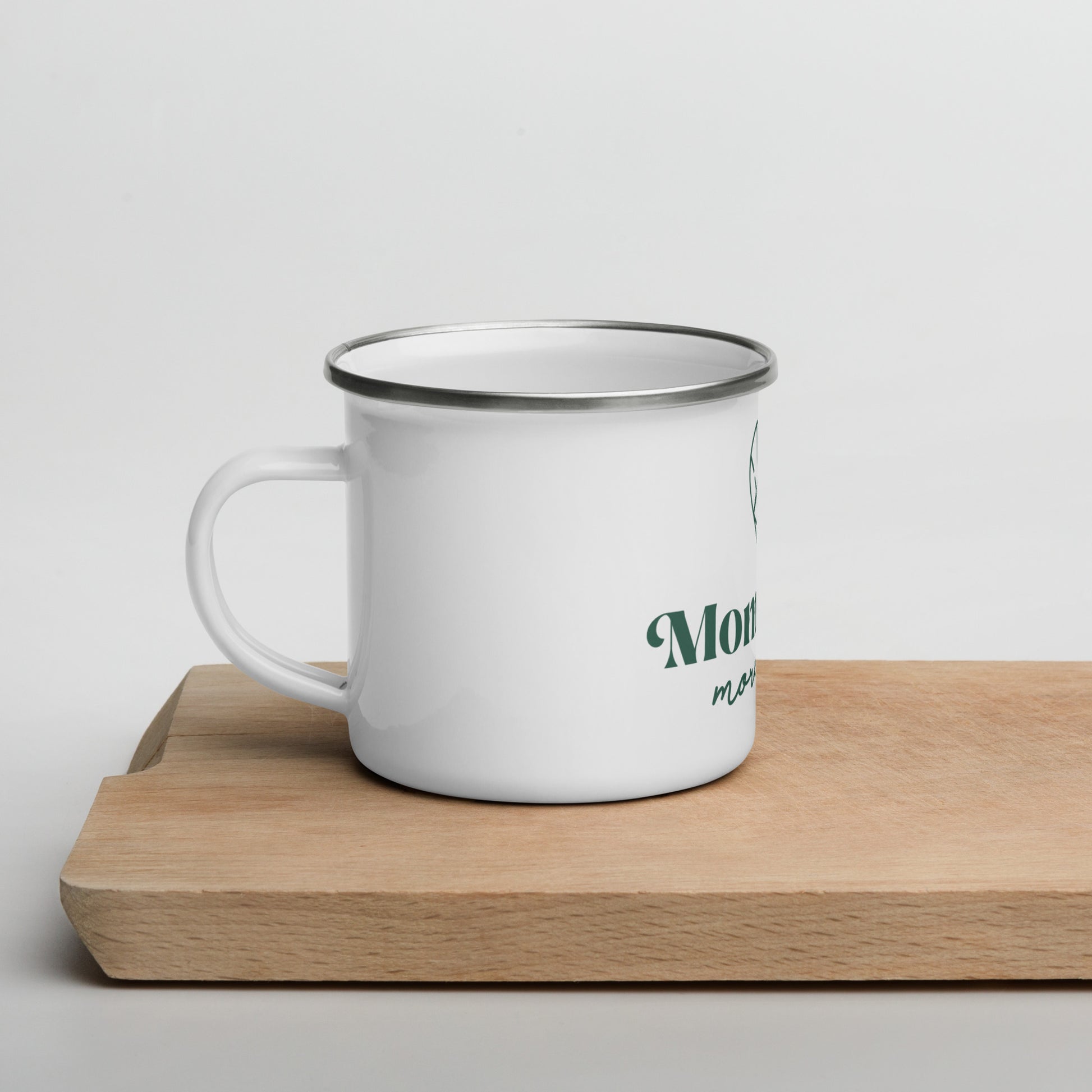 An image of the Moms Have More Fun camping-style mug, featuring a sturdy handle, a charming design, and the brand logo. Perfect for enjoying your favorite hot beverages with a touch of style and fun.